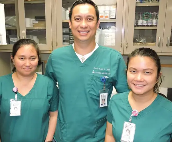 Three nurses in green scrubs standing next to each other.