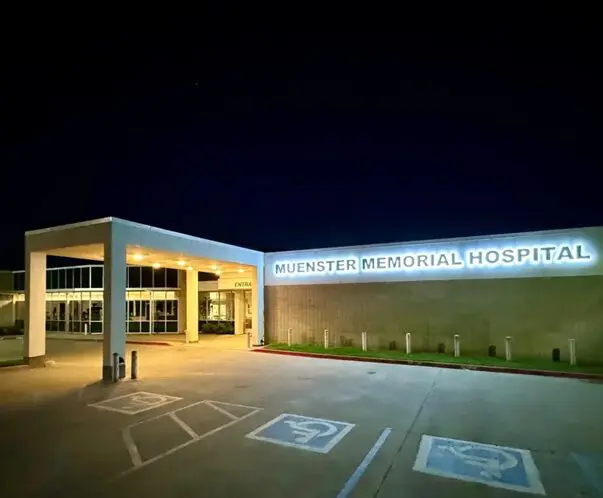 A hospital building with the entrance lit up at night.