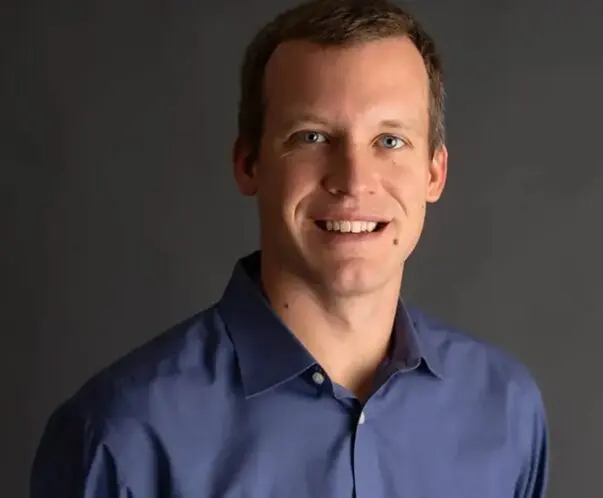 A man in blue shirt smiling for the camera.