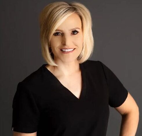 A woman in black shirt standing next to wall.