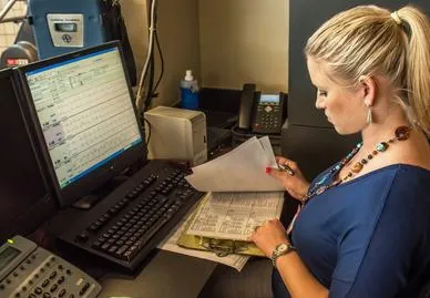 Woman working at desk with computer and paperwork.