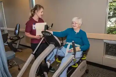 Woman exercising on a recumbent bike with assistance.