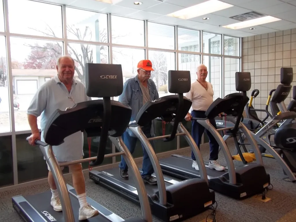 Three men exercising on treadmills at gym.