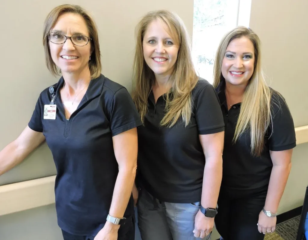 Three women wearing black shirts smiling.