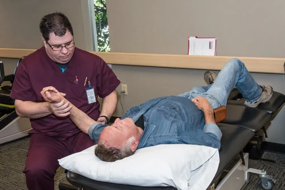 Physical therapist examining patient's arm.